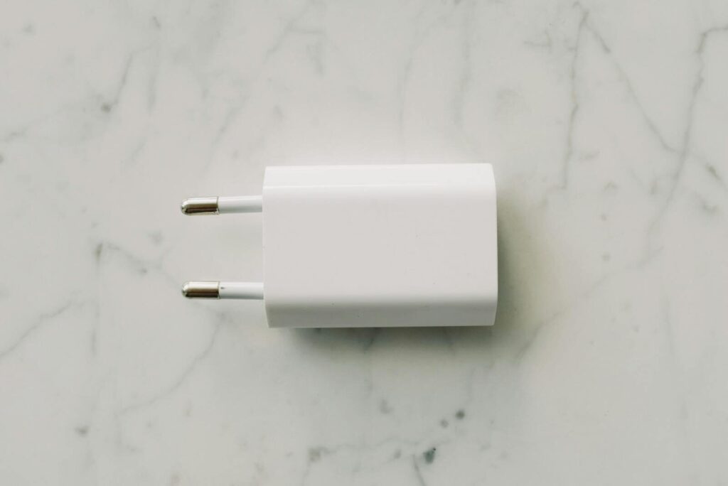 A sleek white power adapter placed on a marble surface, showcasing minimalist design.