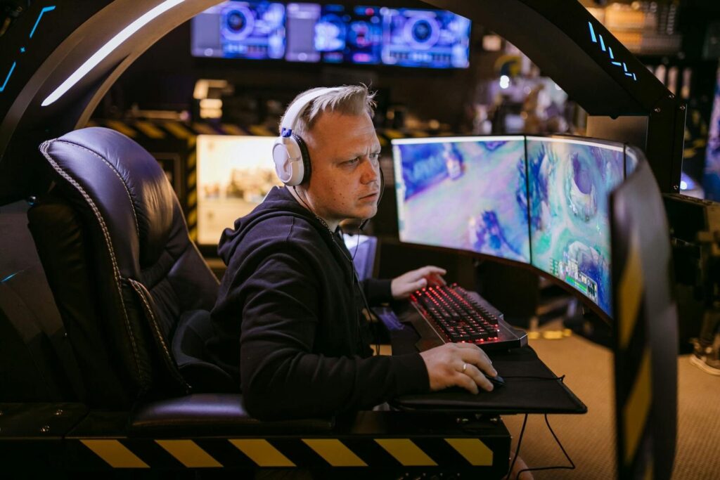 A focused gamer using an advanced multi-monitor setup in a modern gaming chair.